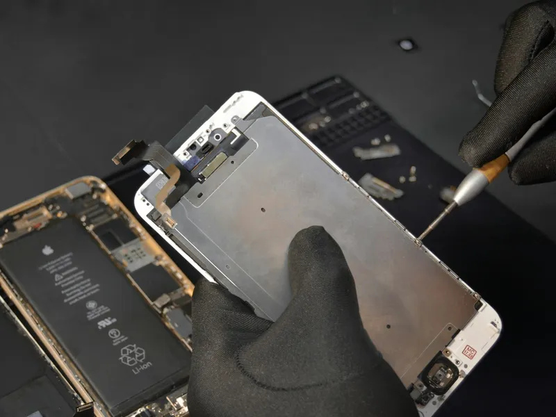 Een technicus vervangt het scherm van een iPhone, de Apple-batterij zit er nog in